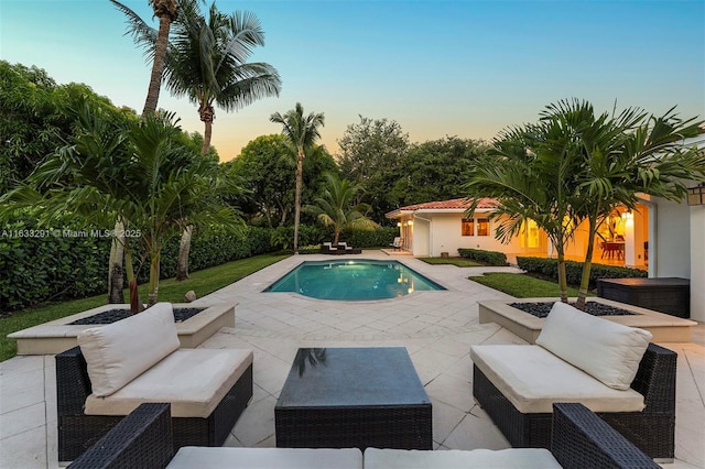 pool at dusk with an outdoor living space and a patio area