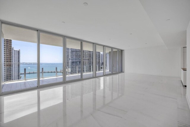 tiled spare room featuring floor to ceiling windows and a water view