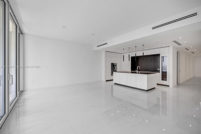 unfurnished living room featuring light tile patterned floors and sink