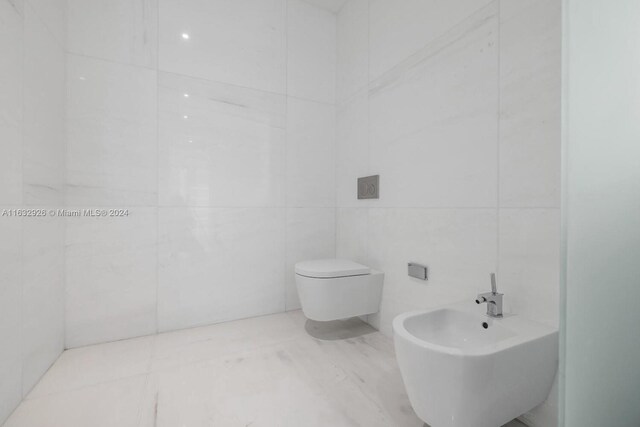 bathroom featuring a bidet, toilet, tile patterned floors, and tile walls