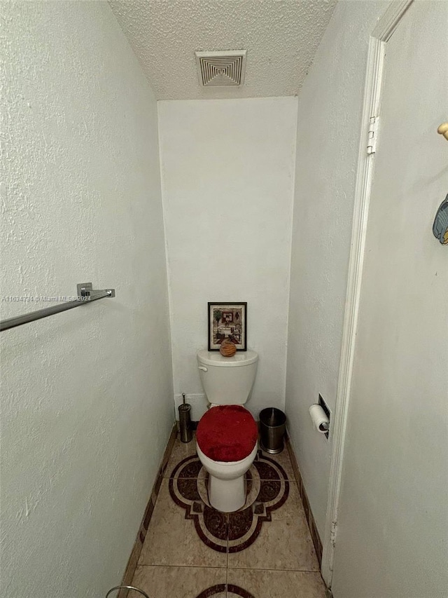 bathroom with toilet, a textured ceiling, and tile patterned flooring