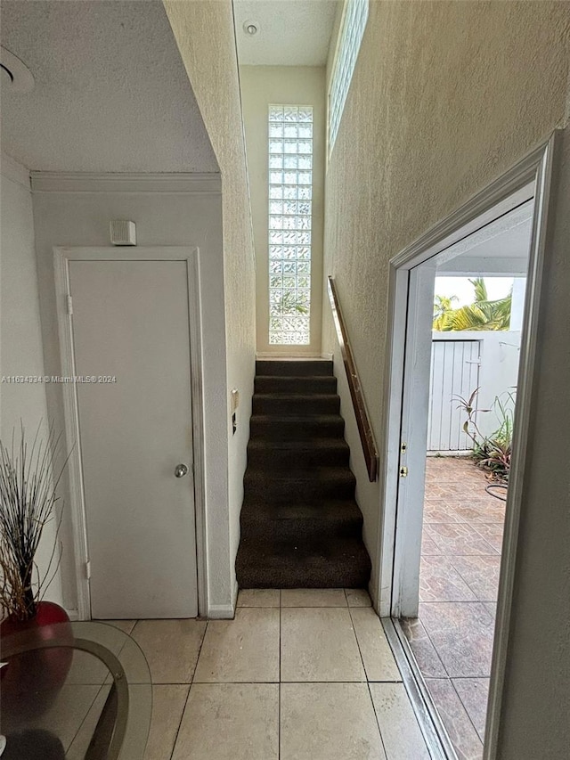 stairway featuring light tile patterned flooring and a textured ceiling