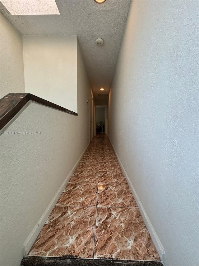 corridor featuring tile patterned floors and a textured ceiling