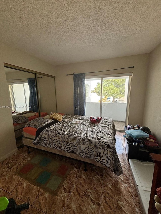 bedroom featuring access to exterior, a textured ceiling, and tile patterned floors