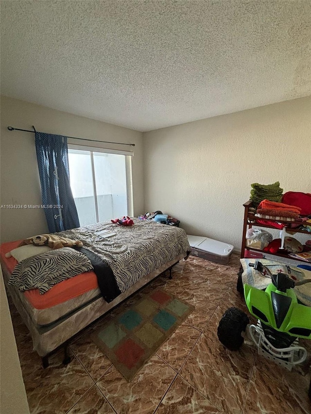 bedroom featuring a textured ceiling and dark tile patterned flooring