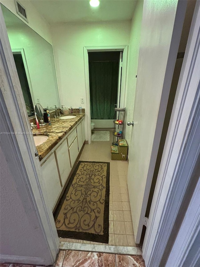 bathroom featuring toilet, tile patterned floors, and double vanity