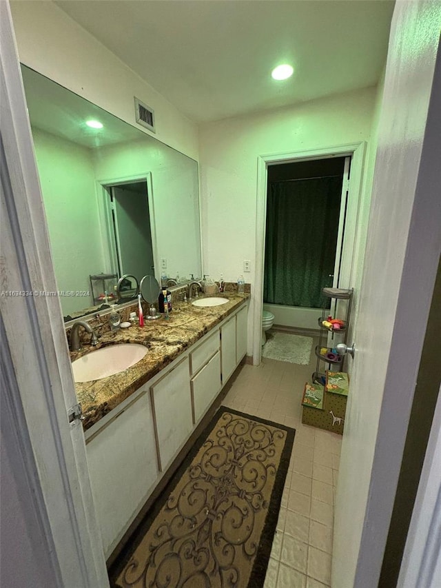 bathroom with toilet, tile patterned flooring, and double vanity