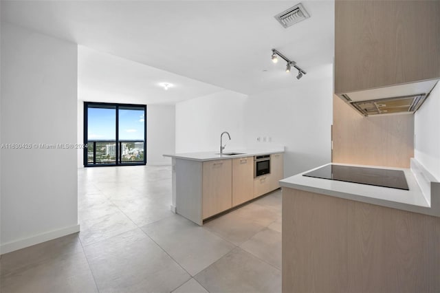 kitchen featuring floor to ceiling windows, rail lighting, black electric stovetop, light brown cabinetry, and sink