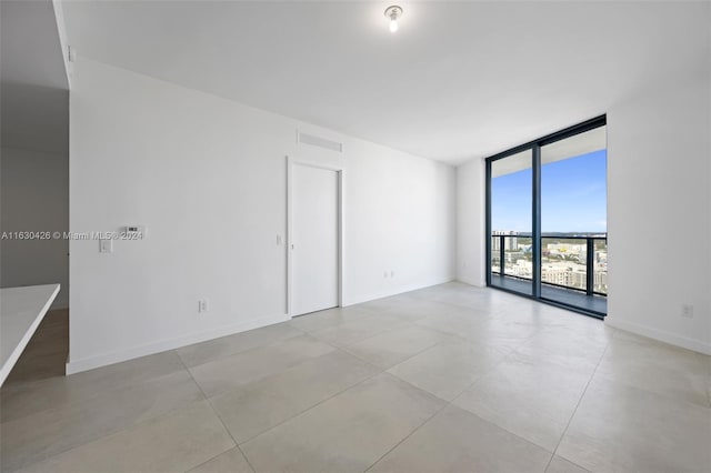 unfurnished room with floor to ceiling windows and light tile patterned floors