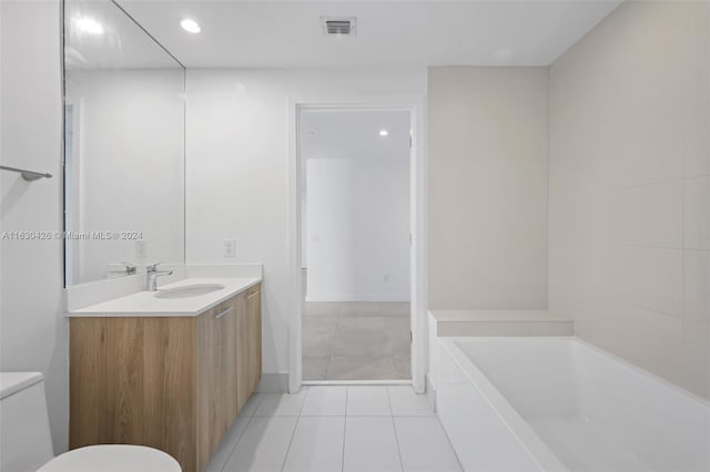 bathroom with a tub, vanity, tile patterned flooring, and toilet