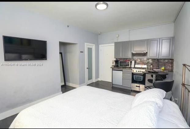 kitchen with tasteful backsplash, white dishwasher, dark hardwood / wood-style floors, stove, and gray cabinetry