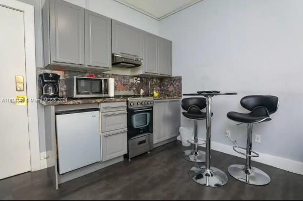 kitchen featuring gray cabinets, high quality range, tasteful backsplash, and fridge