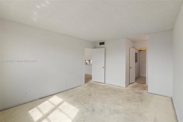 unfurnished bedroom with a textured ceiling, visible vents, and concrete flooring