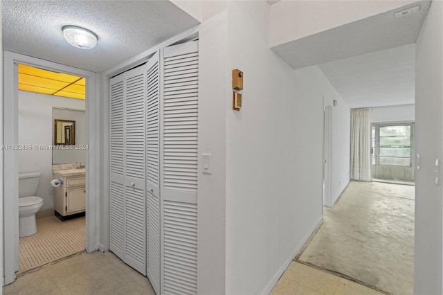 hallway with a textured ceiling and a sink