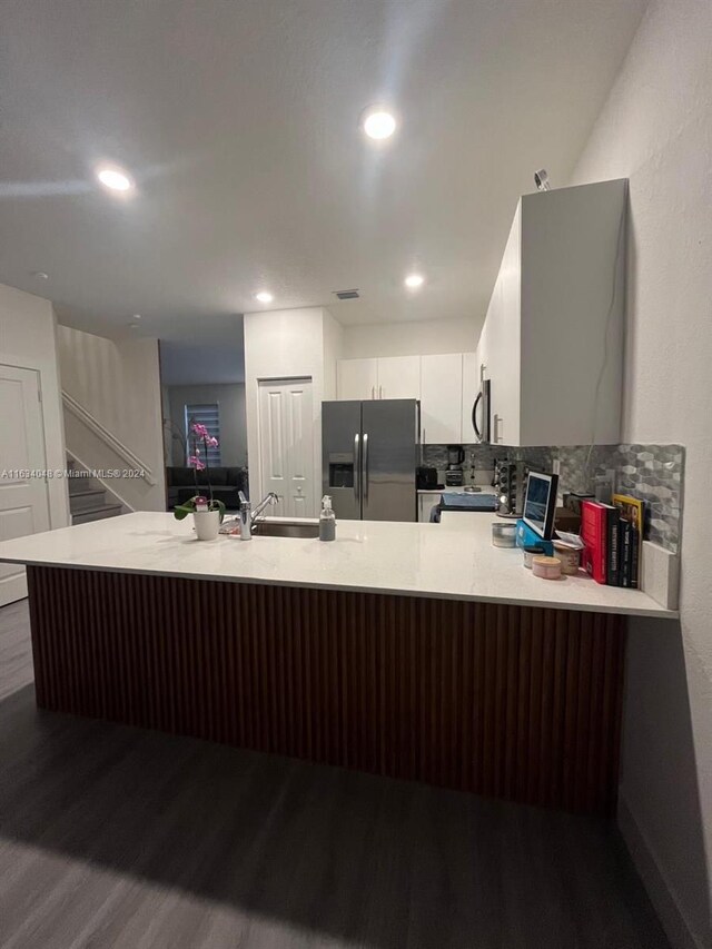 kitchen with backsplash, dark hardwood / wood-style floors, white cabinetry, appliances with stainless steel finishes, and sink