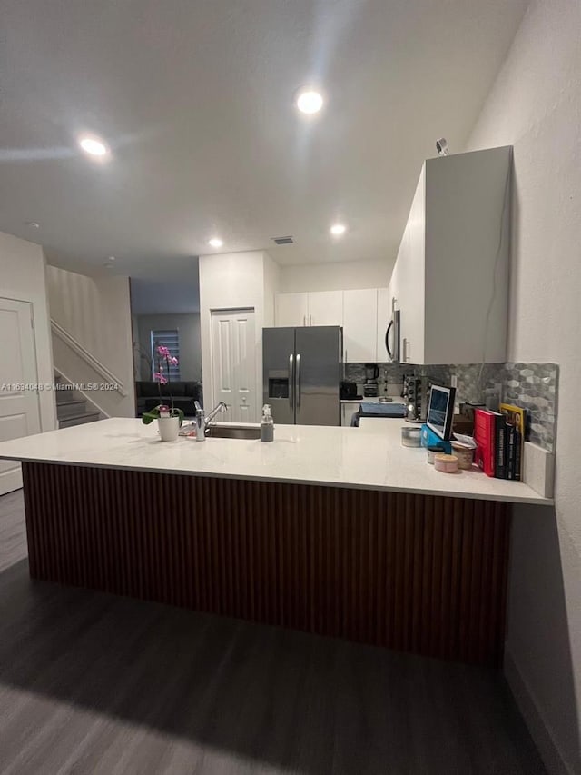 kitchen with appliances with stainless steel finishes, light countertops, a sink, and wood finished floors