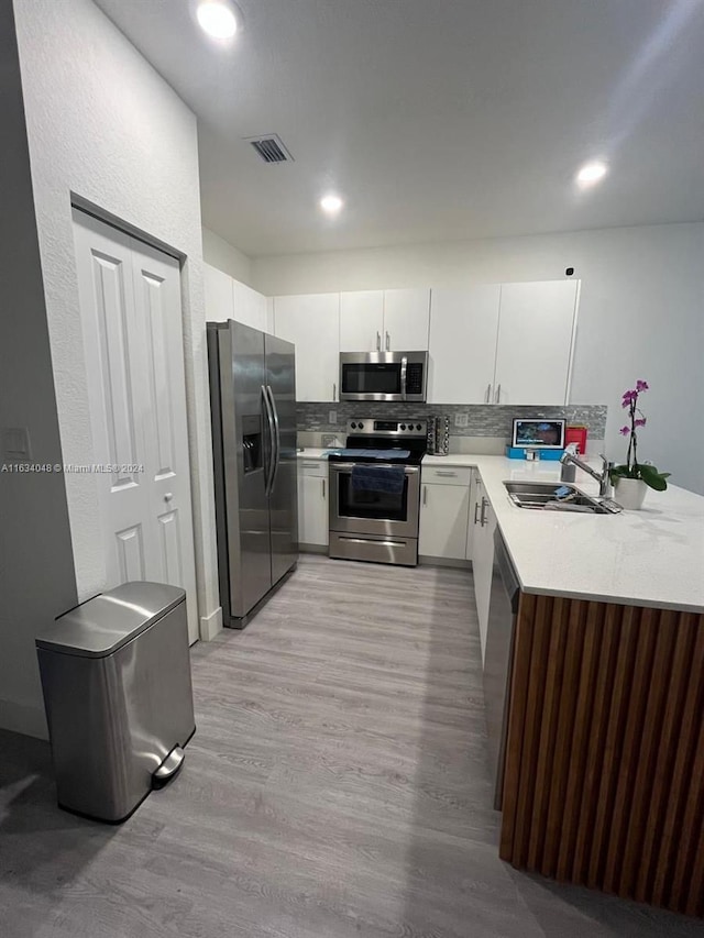 kitchen featuring a peninsula, a sink, visible vents, light countertops, and appliances with stainless steel finishes