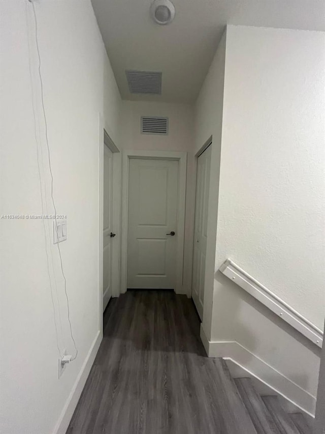 corridor featuring dark wood-type flooring, visible vents, and baseboards