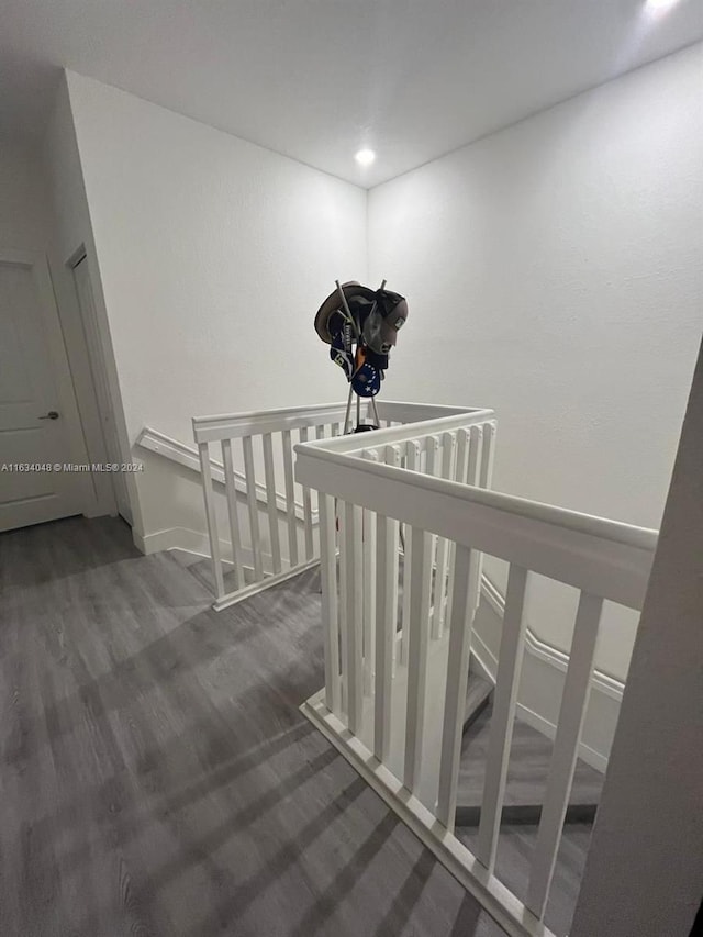 corridor featuring wood finished floors, an upstairs landing, and baseboards