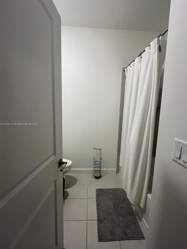 full bath with baseboards, shower / bathtub combination with curtain, toilet, and tile patterned floors