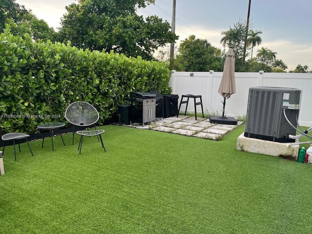 view of yard featuring central AC, fence, and a patio