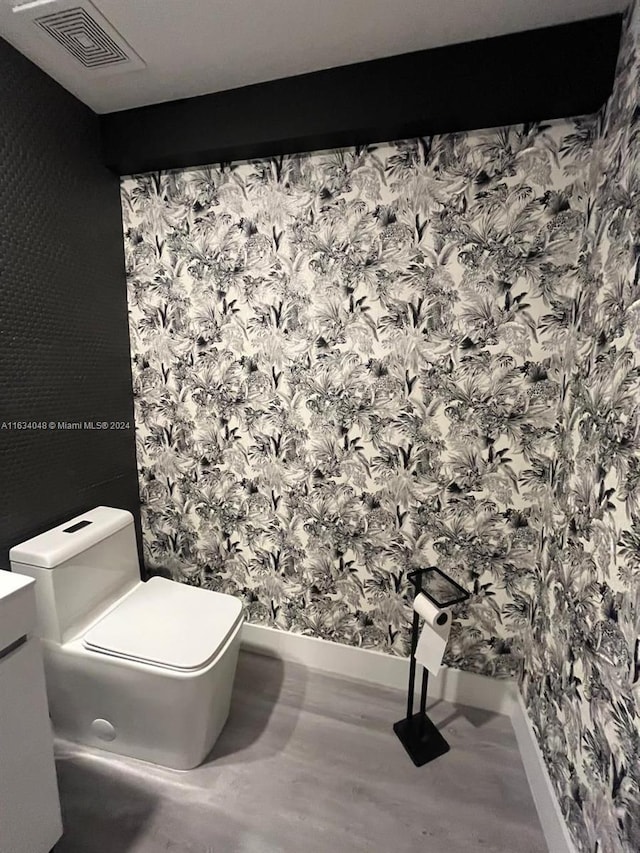 bathroom with toilet, visible vents, and wood finished floors