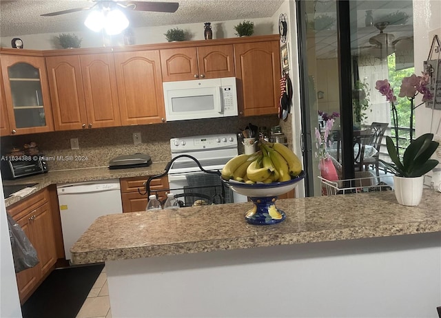 kitchen with white appliances, a textured ceiling, light tile patterned flooring, ceiling fan, and glass insert cabinets