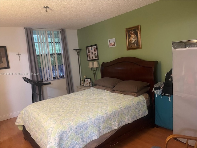 bedroom with a textured ceiling and hardwood / wood-style floors