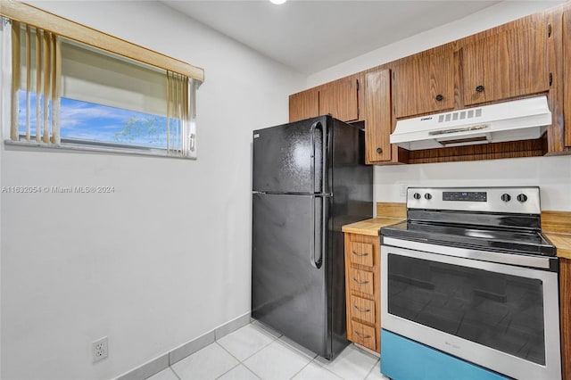 kitchen with black refrigerator, light tile patterned flooring, and electric stove