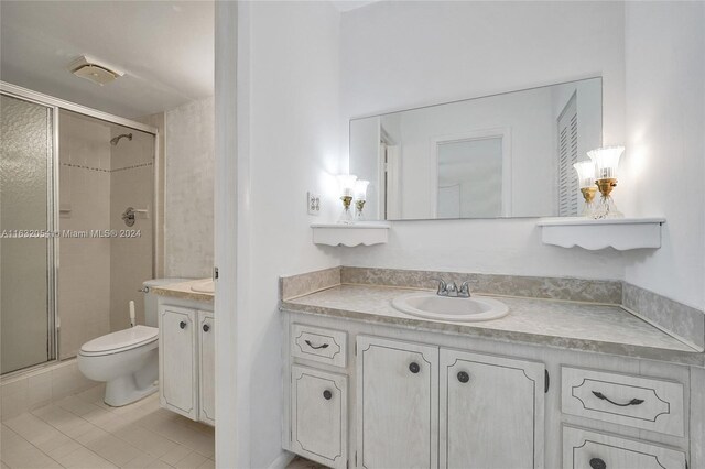 bathroom with tile patterned floors, vanity, an enclosed shower, and toilet