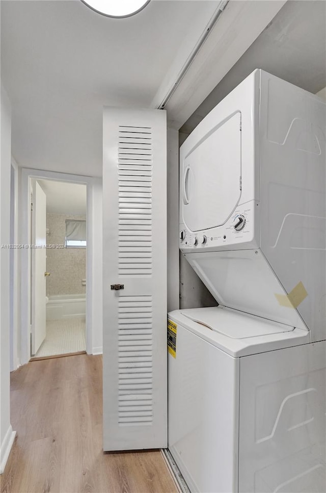 clothes washing area with stacked washer and dryer and light wood-type flooring