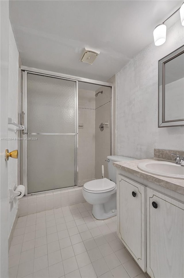 bathroom featuring a shower with shower door, tile patterned floors, toilet, and vanity