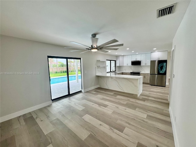 unfurnished living room with sink, light wood-type flooring, and ceiling fan