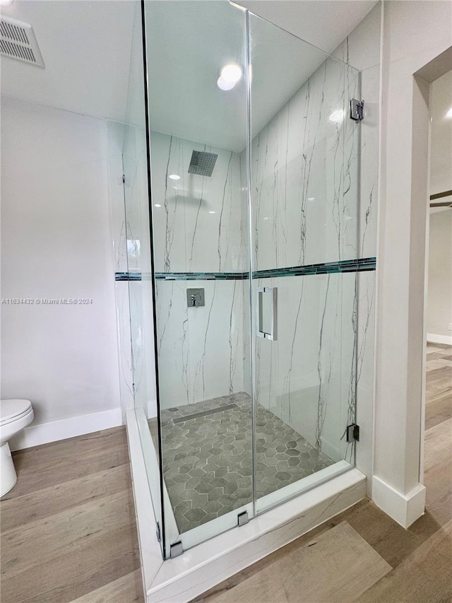 bathroom featuring wood-type flooring, toilet, and an enclosed shower