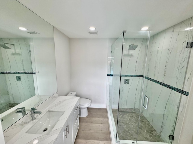 bathroom with a shower with shower door, vanity, hardwood / wood-style flooring, and toilet