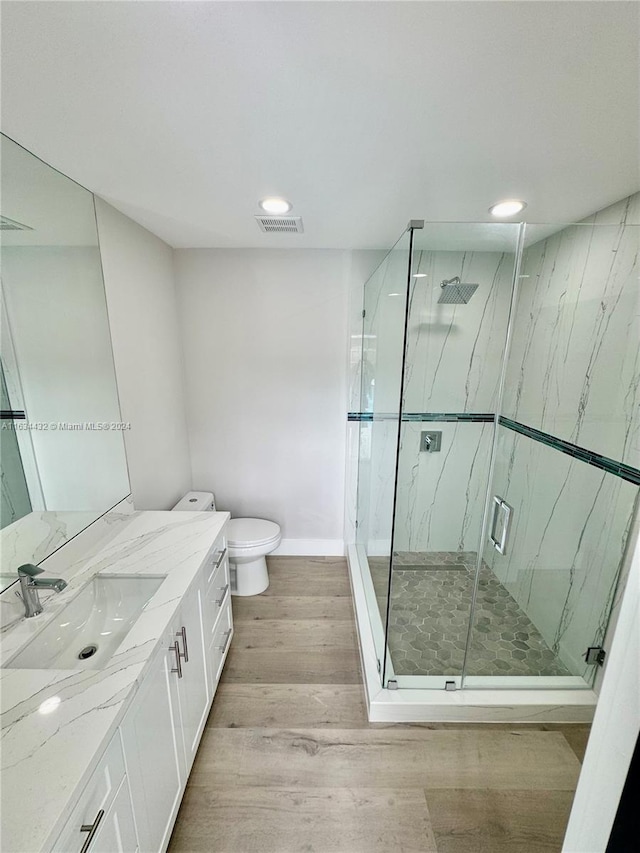 bathroom with toilet, hardwood / wood-style floors, vanity, and an enclosed shower