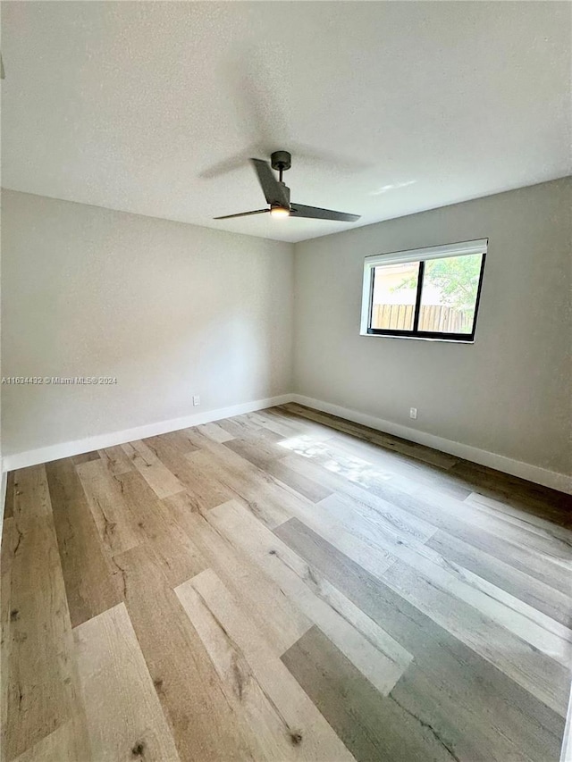 spare room with a textured ceiling, ceiling fan, and light wood-type flooring