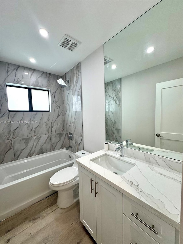 full bathroom featuring hardwood / wood-style flooring, toilet, vanity, and tiled shower / bath