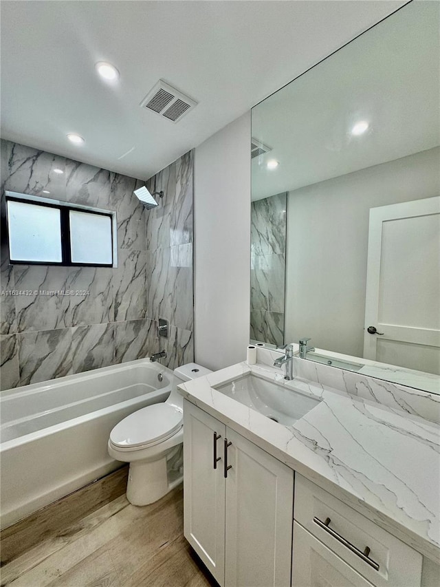 full bathroom with hardwood / wood-style flooring, toilet, vanity, and tiled shower / bath