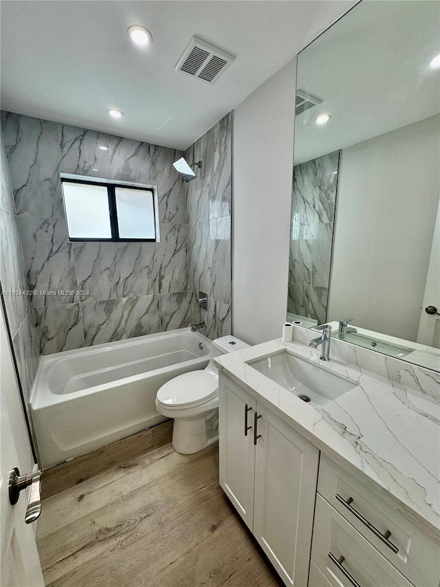 full bathroom featuring vanity, tiled shower / bath, toilet, and hardwood / wood-style floors