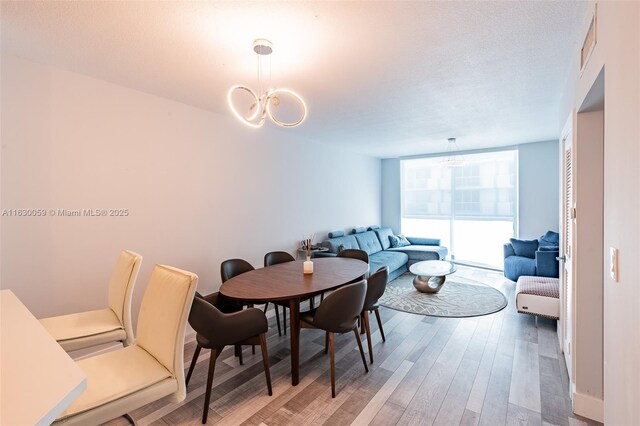 dining room with hardwood / wood-style floors, a textured ceiling, and a notable chandelier