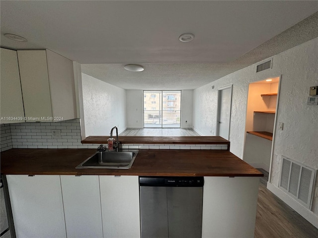 kitchen with light wood-type flooring, sink, dishwasher, wood counters, and backsplash