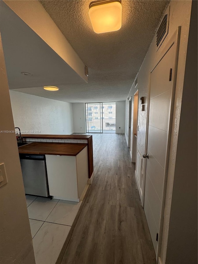 hallway featuring sink, a textured ceiling, and light hardwood / wood-style floors