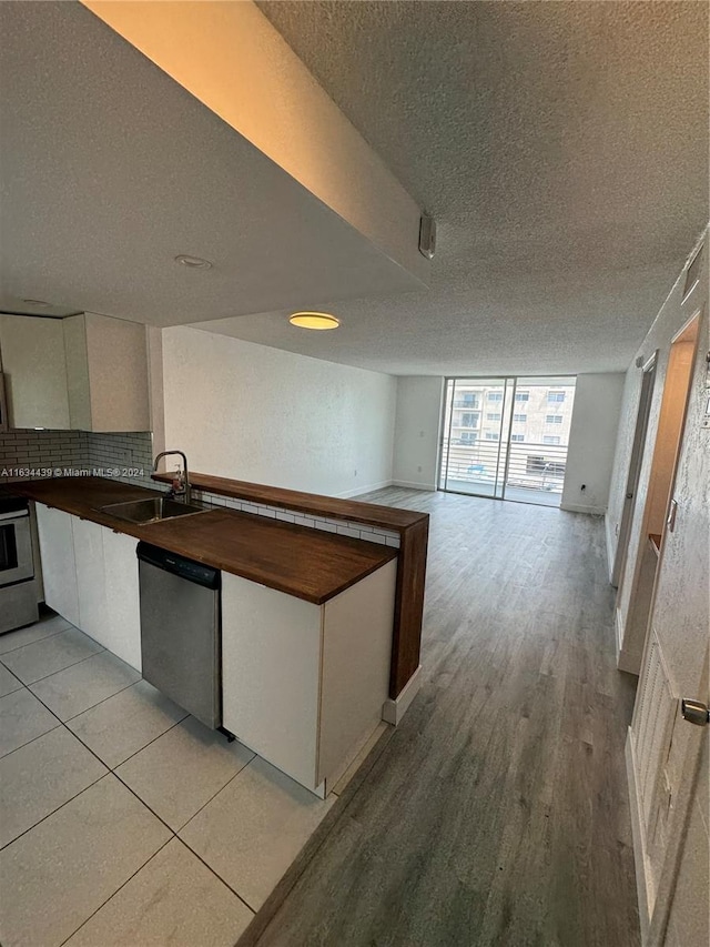 kitchen featuring light hardwood / wood-style floors, sink, dishwasher, and a textured ceiling