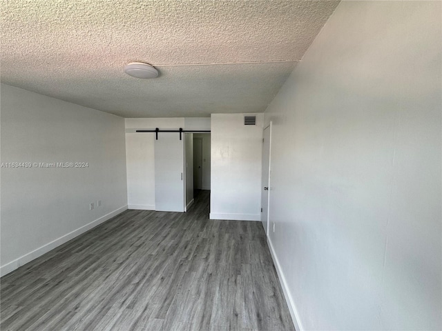 unfurnished bedroom featuring a barn door, a textured ceiling, and wood-type flooring