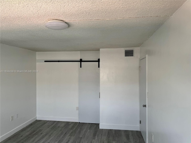 interior space with dark hardwood / wood-style flooring, a barn door, and a textured ceiling