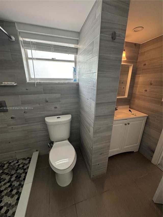 bathroom with vanity, toilet, tile patterned flooring, and tile walls