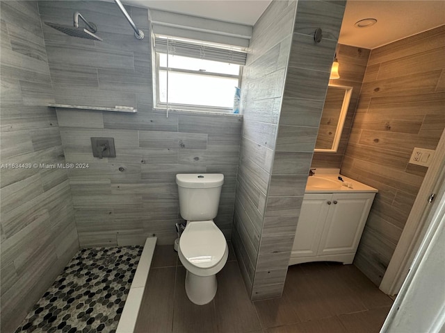 bathroom featuring tiled shower, toilet, vanity, tile walls, and tile patterned floors