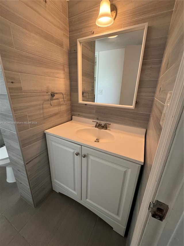 bathroom with tile patterned floors, vanity, tile walls, and toilet