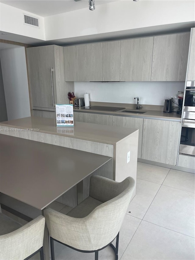 kitchen featuring light tile patterned flooring, cooktop, and sink